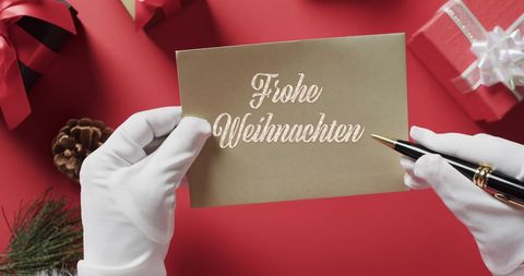 Santa Claus Writing Christmas Greeting Card in German Hug