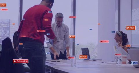 Leaning coworker reviewing papers during team brainstorm with floating social media badges