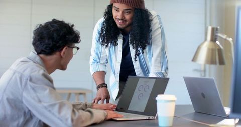 Two coworkers collaborating over laptop displaying analytics charts in modern workspace