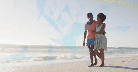 Romantic couple walking arm in arm on seaside beach