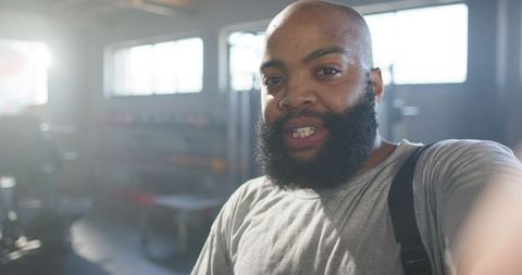 African man taking gym selfie after workout with beard and backpack strap