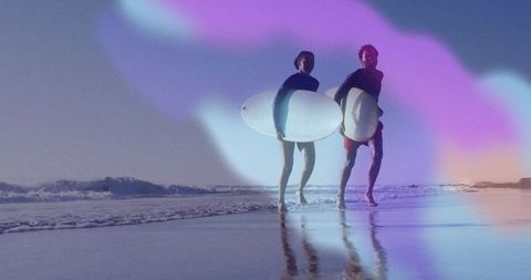 Couple with surfboards enjoying ocean adventure under vivid sky