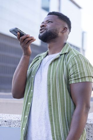 Black man talking into smartphone outside modern urban office building