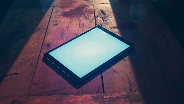Tablet on wooden table illuminated by sunlight