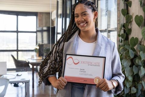 Confident businesswoman holding recognition certificate in modern office