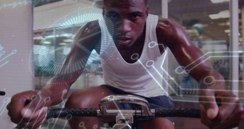 Athlete pushing on stationary bike with futuristic hud overlay, intense cycling training