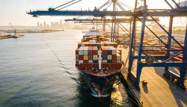 Container ship approaching quay under gantry cranes at sunrise port logistics hub
