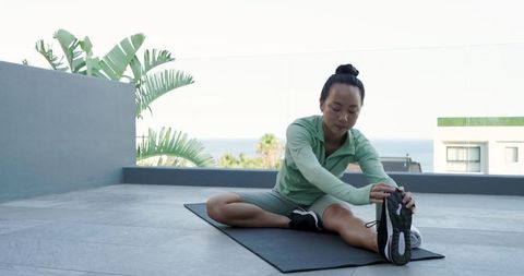 Woman practicing seated hamstring stretch on rooftop terrace