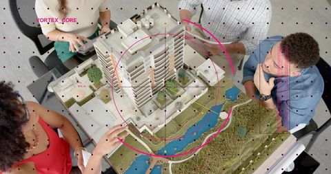Collaborating team reviewing architectural scale model and digital overlay for urban design
