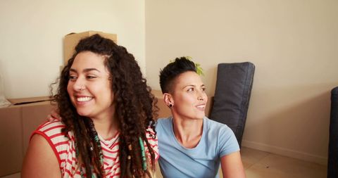 Happy Women Friends Moving In Together with Boxes