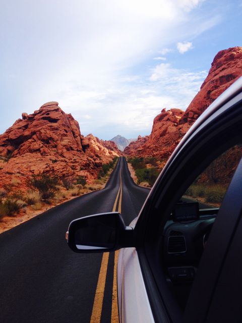Perfect for promoting adventure travel, road trips, or travel destinations involving dramatic desert scenery with red rock formations. Suitable for blogs, package tours, or ads targeting active and adventurous travelers. Illustrates freedom and excitement of open road adventures.