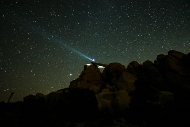 Traveler Shining Light on Starry Night Rocks and Stars - Download Free Stock Photos Pikwizard.com