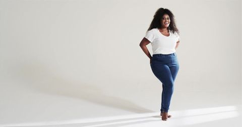 Confident Woman in Casual Attire Standing in Minimalist Studio