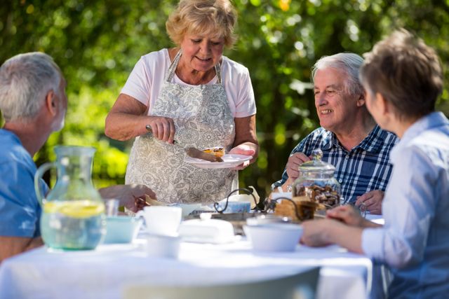 Senior Woman Serving Breakfast to Friends in Garden - Download Free Stock Photos Pikwizard.com