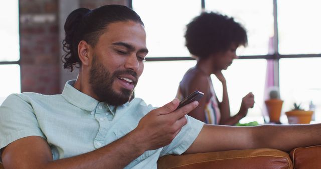 Young Man Smiling While Using Smartphone in Cozy Home Setting - Download Free Stock Images Pikwizard.com