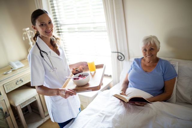 Female doctor serving breakfast to a senior woman in a bedroom at home. The senior woman is sitting up in bed, smiling, and holding a book. This image can be used for themes related to home healthcare, elderly care, medical services, and caregiving. It is ideal for illustrating articles, brochures, and websites focused on healthcare services, senior living, and patient care.
