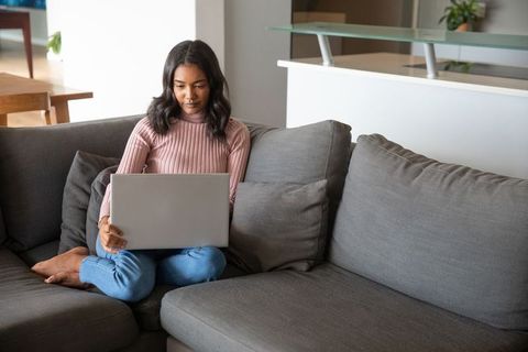 Woman Using Laptop on Modern Grey Sofa in Cozy Living Room