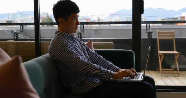 Young Man Working on Laptop at Home with City View - Download Free Stock Images Pikwizard.com