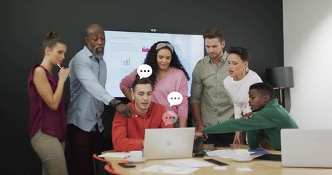 Diverse team collaborating around laptop during analytics presentation in modern boardroom