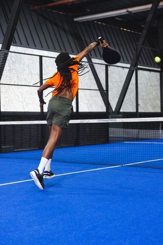 Agile Athlete in Dynamic Padel Action on Blue Court