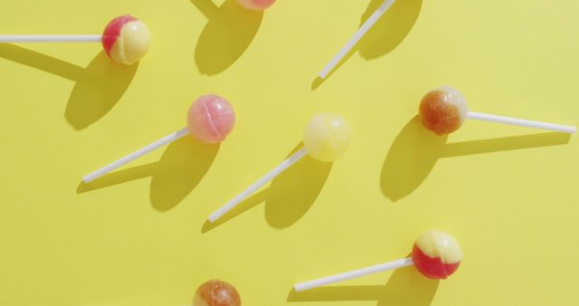 Image of multicoloured lollipops on yellow background. colourful fun food, candy, snacks and sweets concept.