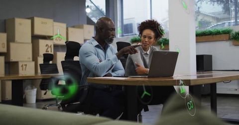 Coworkers discussing sustainability using digital tools in a modern office