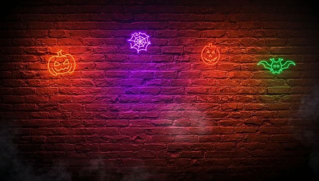 Neon Halloween Icons Illuminating Brick Wall at Night