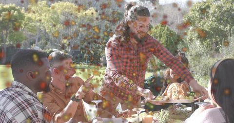 Bearded Man Serving Roasted Chicken at Sunlit Backyard Dinner Party with Friends