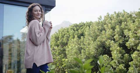 Relaxed Woman Enjoying Coffee on Balcony Overlooking Scenic Nature