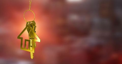 Golden house keyring and keys hanging on chain with warm bokeh gradient background