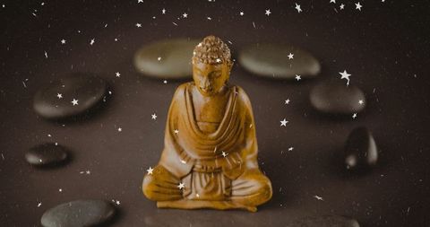 Wooden buddha statue amidst stones with starry overlay