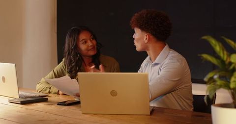 Colleagues Discussing Project at Office Table with Laptops