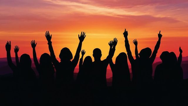 Silhouetted group raising hands on sunset ridge celebrating unity and togetherness