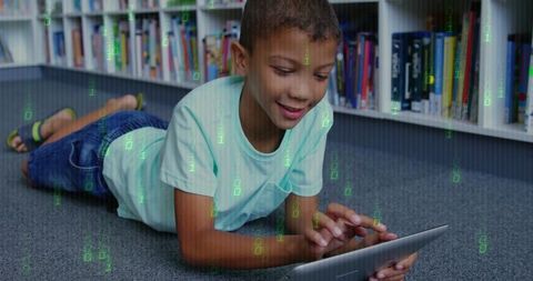 Young boy using tablet on library floor with digital binary overlay for STEM learning