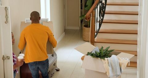 Couple Moving Boxes into New Home Entrance on Sunny Day