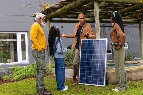 Multigenerational african american family discussing solar panel installation in backyard garden