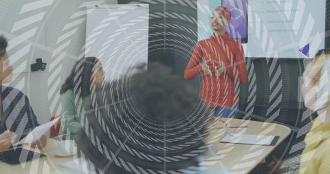 Female Leader Presenting to Diverse Team in Meeting Room Wearing Red Sweater and Headwrap