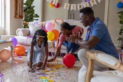African american family celebrating lively birthday at home with balloons, confetti, joy