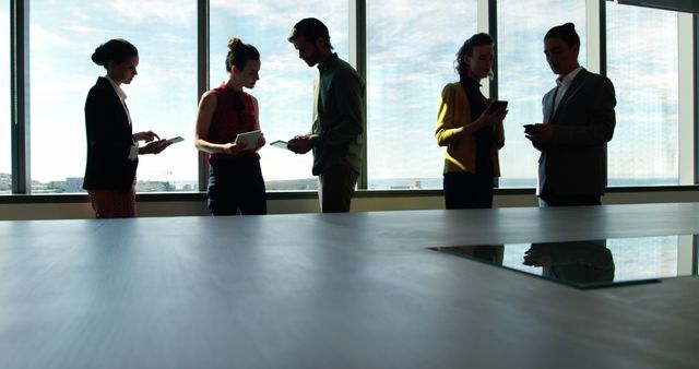 Silhouetted Business Professionals Collaborating in Modern Office - Download Free Stock Images Pikwizard.com