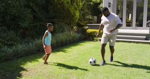Playful Father-Son Bonding with Soccer in Sunny Backyard