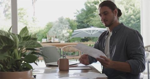 Focused young man working remotely while studying documents