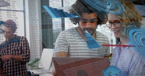 Developers collaborating over holographic data dashboard in modern open-plan office