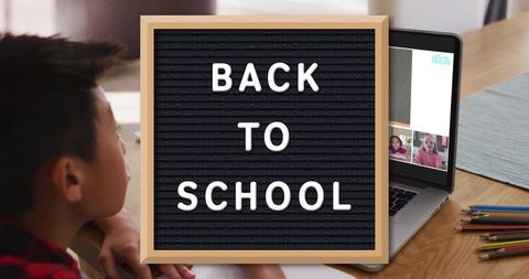 Back to school letter board on desk with child attending virtual class