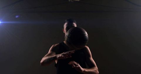 Intense Male Basketball Player Dribbling Under Gym Spotlight