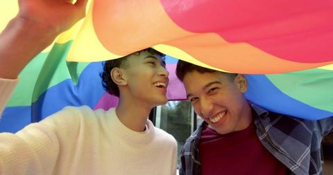 Joyful Friends Celebrating Under Rainbow Flag Outdoors