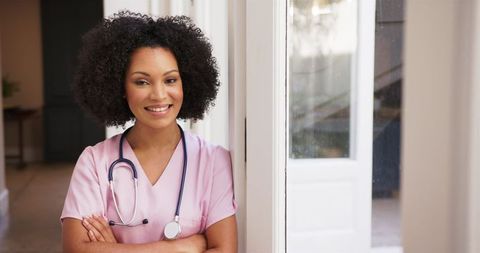 Smiling Nurse in Pink Scrubs with Stethoscope by Window