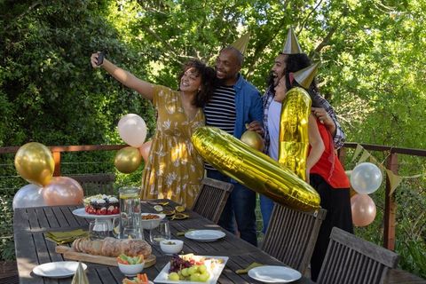 Friends Celebrating Outdoors Taking Selfie Party Hats Balloons Wooden Deck Gathering