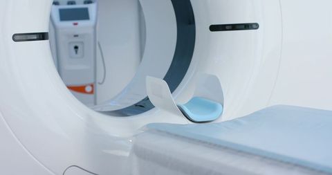 Modern ct scanner gantry with sliding patient table and blue headrest radiology suite