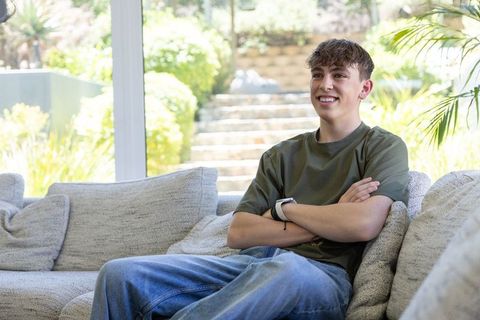 Teen relaxing on sofa near sunlit window wearing smartwatch and casual jeans