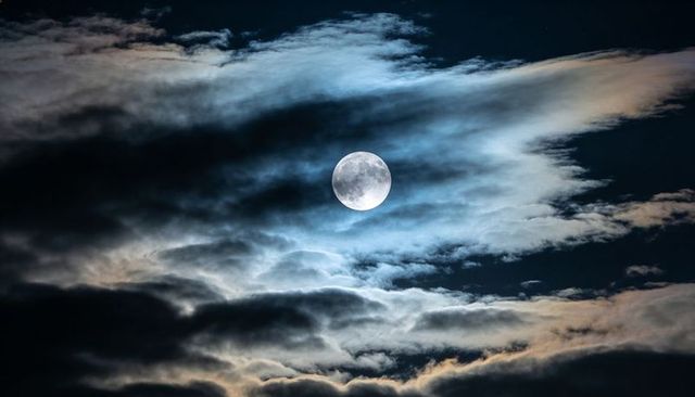 Full Moon Bathing Night Sky in Cool Light with Layered Clouds and Subtle Halo